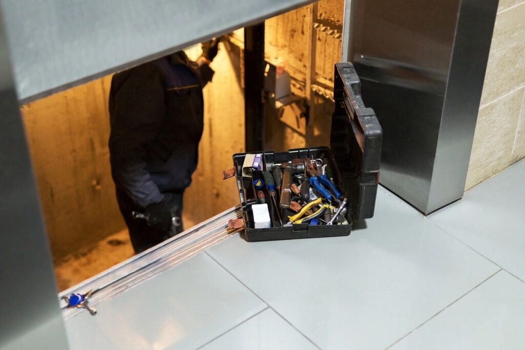 Elevator maintenance with open toolbox nearby.